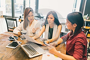 Group of young Asian women or college students in serious business meeting or project brainstorm discussion at coffee shop photo