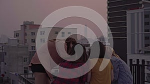 Group of young asian women people dancing and raising their arms up in air to the music played by dj at sunset urban party on roof