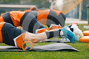 Group of Young Athletes on Stretching Outdoor Session with Foam Rollers and Mats