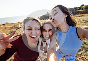 A group of young attractive multiethnic women take selfies and laugh outdoors