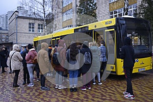 Group of young boys and girls standing in front of the school bus ready to get on