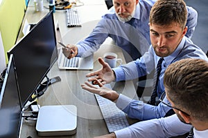 Group of young business men in formalwear working using computers while sitting in the office