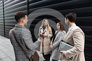 Group of young business people, job candidates standing in front of the office building waiting to be called to meeting with the