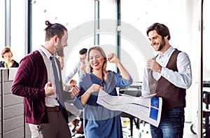 Group of young business people in an office, expressing excitement.