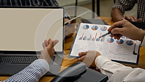 A group of young business people who are confidnt in analyzing data using graphs and computers while working as a Tim for busi photo