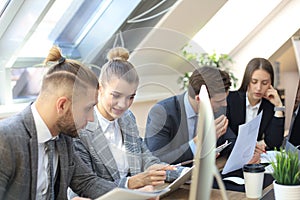 Group of young business people working, communicating while sitting at the office desk together with colleagues