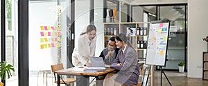 Group of young business people working and communicating while sitting at the office desk together with colleagues