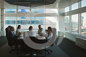 Group of young business people working and communicating while sitting at the office desk together with colleagues