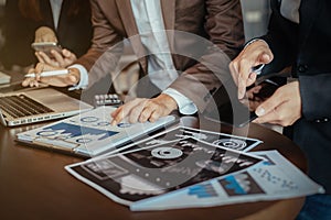 Group of young business people working and communicating while sitting at the office desk together with colleagues. Full