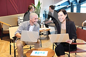 Group of young business people working and communicating while sitting at the office desk together with colleagues sitting in the