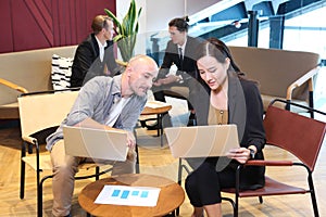 Group of young business people working and communicating while sitting at the office desk together with colleagues sitting in the