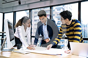 A group of young business people working together while sitting at their desks in the office