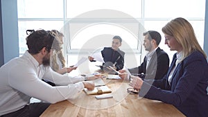 Group of young businessman at the negotiating table in the office. Colleagues look through documents. a business meeting