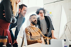 Group of young businesspeople with computer working together in a modern office.