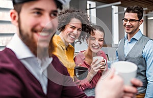 A group of young businesspeople with cup of coffee standing in office.