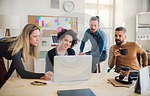 Group of young businesspeople with laptop having meeting in a modern office.