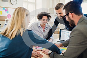 Group of young businesspeople with laptop working together in a modern office.