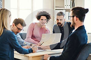 Group of young businesspeople with laptop working together in a modern office.