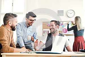 Group of young businesspeople with laptop working together in a modern office.