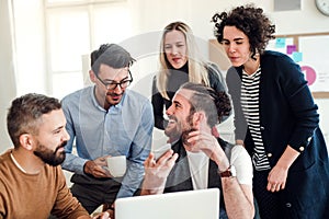 Group of young businesspeople with laptop working together in a modern office.