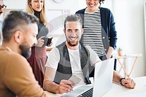 Group of young businesspeople with laptop working together in a modern office.