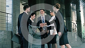 Group of young businesspeople meeting near the business center and greeting each other