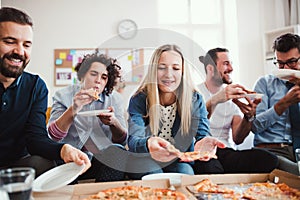 Group of young businesspeople with pizza having lunch in a modern office.