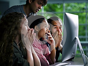 Group of young businesspersons looking intently at the screen