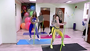 Group of young caucasian women doing exercises with stick standing in fitness studio