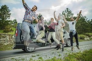 Group of young cheerful friends jumping having fun outdoors on the road