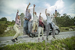 Group of young cheerful friends jumping having fun outdoors on the road