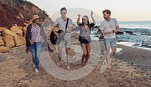 Group of young and cheerful friends walking on beach