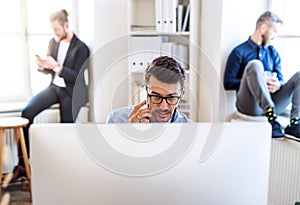 Group of young businesspeople with smartphone working together in a modern office.