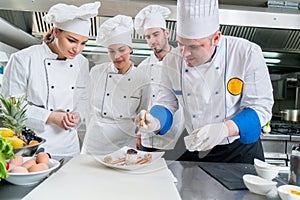 A group of young chefs prepairing meal in luxury restaurant photo