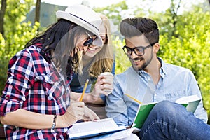 Group of young college students having fun while discussing homework on a park bench