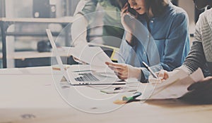 Group of young coworkers working together in modern coworking studio.Woman using smartphone for talking with partners