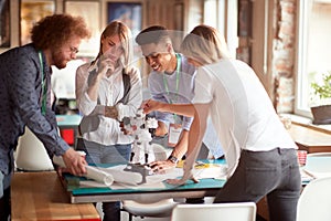 Group of young creative people is analyzing a robot toy at work in the office