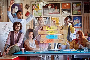 Group of young creative people is throwing money while posing for a photo at their workplace