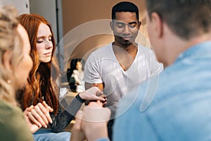 Group of young diverse multiethnic people holding hands together during the psychological therapy, meditating and