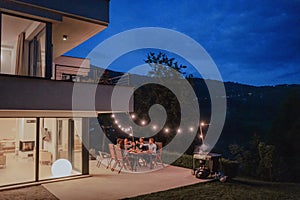 A group of young diverse people having dinner on the terrace of a modern house in the evening. Fun for friends and