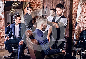 Group of young elegant positive mens pose in interior of barbershop.