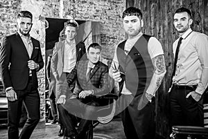 Group of young elegant positive mens pose in interior of barbershop.