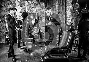 Group of young elegant positive mens pose in interior of barbershop.