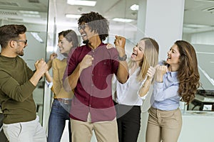 Group of young excited business people with hands up  standing in office
