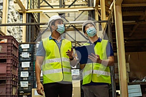 Group of young factory warehouse workers wearing a protective face mask while working in logistic industry. Asian and