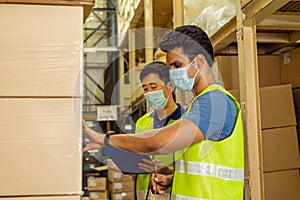 Group of young factory warehouse workers wearing a protective face mask while working in logistic industry. Asian and