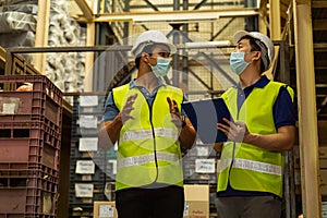 Group of young factory warehouse workers wearing a protective face mask while working in logistic industry. Asian and