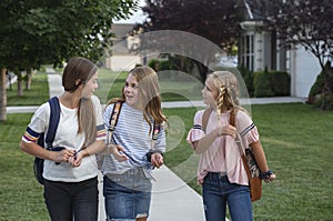 Group of young female friends and students talking together as they walk home school for the day