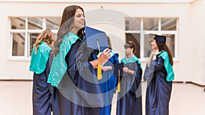 A group of young female graduates. Female graduate is smiling against the background of university graduates