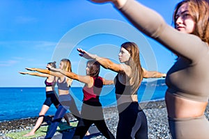 Group of young females practicing yoga on the seaside